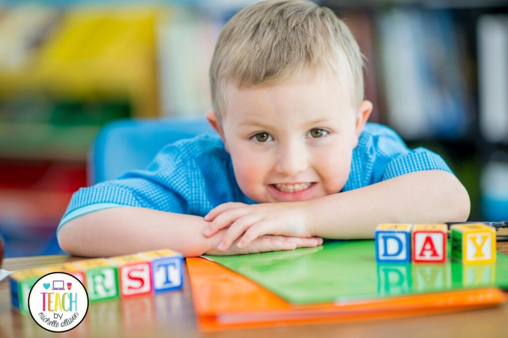 Picture of a child sitting at a desk. On the desk are blocks spelling out "first day of school".